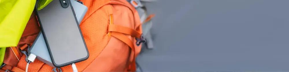 The smartphone is being charged with a portable charger. Power bank with a mobile phone on a sleeping bag with a backpack.